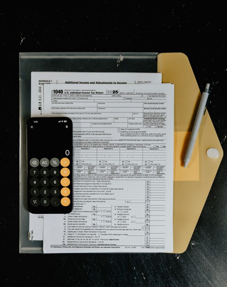 Close-up of someone reviewing multiple tax documents and pay stubs at a kitchen table.